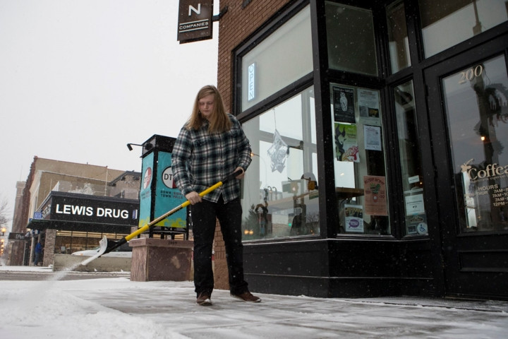 Một phụ nữ đang dọn tuyết bên ngoài quán cà phê của mình.