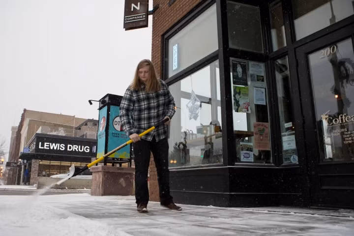 Một phụ nữ đang dọn tuyết bên ngoài quán cà phê của mình.