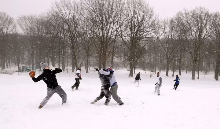 Bất chấp trời tuyết, nhiều người vẫn tham gia các hoạt động ngoài trời. Ảnh: Một nhóm thanh niên chơi bóng bầu dục trong công viên Cobbs ở New York.