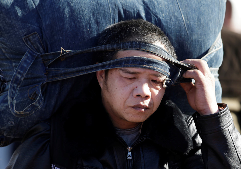 Một người đàn ông vác theo đồ đạc để về quê ăn tết. Với sự phát triển cơ sở hạ tầng của Trung Quốc trong những năm gần đây, đặc biệt là các tuyến tàu cao tốc, hơn một nửa số người đi tàu sẽ có thể về nhà trong vòng 12 giờ. Ảnh: Reuters.