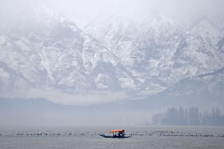 Một người chèo thuyền giữa cơn mưa tuyết trên hồ Dal ở Srinagar ngày 21/1/2019.