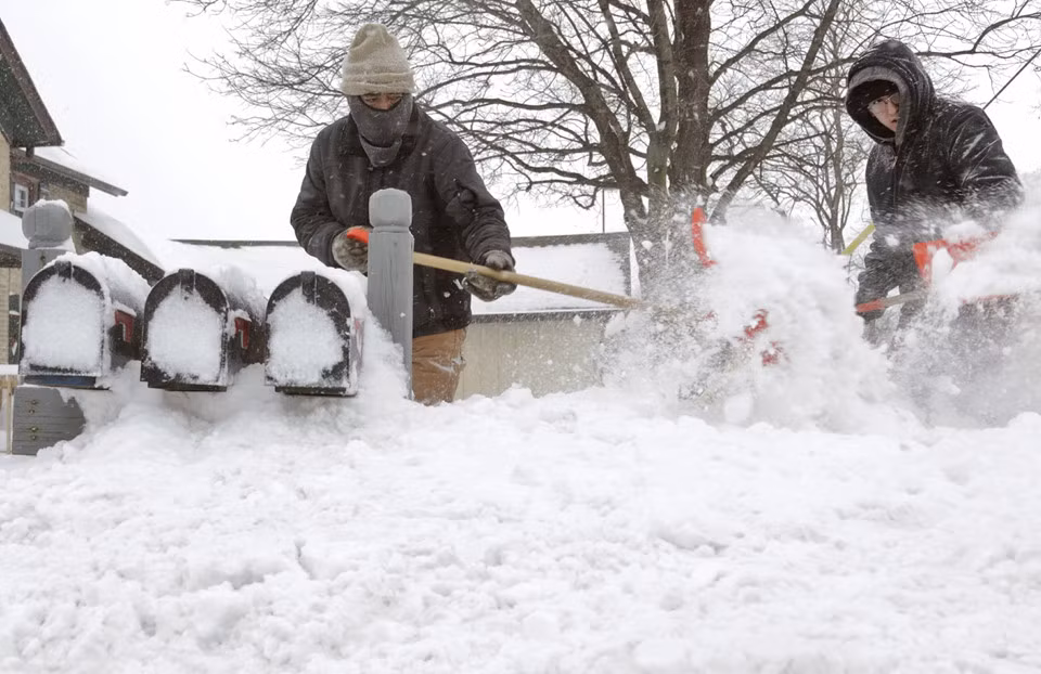Ausencio Castaneda cùng con trai Ausencio Castaneda Jr. đào tuyết để tới được hòm thư của gia đình ở bang Wisconsin, ngày 28/1. Ảnh: AP.