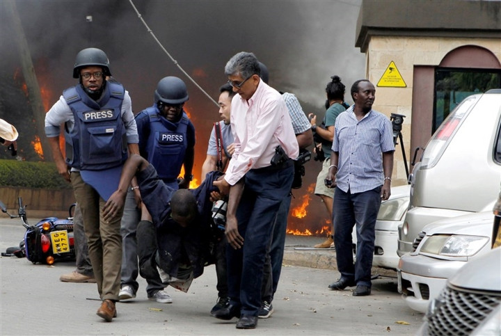 Lực lượng cứu hộ và nhà báo đang sơ tán một nạn nhân khỏi hiện trường. (Ảnh Reuters)
