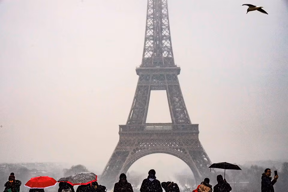 Du khách ngắm nhìn tháp Eiffel khi tuyết rơi nhẹ ở thủ đô Paris của Pháp. Nhà điều hành tàu SNCF đã đưa ra cảnh báo về sự chậm trễ có thể xảy ra đối với các chuyến tàu cao tốc trong khu vực. Người dân Paris cũng được cảnh báo về sự gián đoạn dịch vụ trên một số tuyến metro và hàng chục tuyến xe buýt.