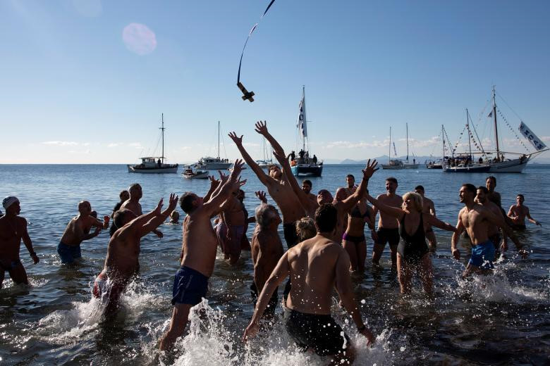 Các tín đồ Chính thống giáo nhảy lên để bắt một cây thánh giá bằng gỗ trong lễ kỷ niệm ngày Lễ Hiển Linh ở vùng ngoại ô phía nam Faliro, Athens, Hy Lạp. Tại các quốc gia khác như Ba Lan, hàng trăm nghìn người đã tham gia vào các đám rước Lễ Hiển Linh đầy màu sắc tại hơn 700 địa điểm trên cả nước.