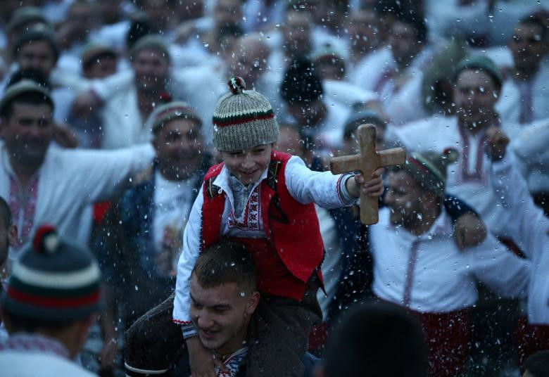 Một cậu bé cầm thánh giá bằng gỗ khi những người đàn ông nhảy múa trong vùng nước băng giá của sông Tnudzha trong Lễ Hiển Linh ở thị trấn Kalofer, Bulgaria. Hàng nghìn tín đồ Cơ đốc giáo Chính thống đã ngâm mình trong các hồ và sông băng trên khắp Bulgaria để tìm thánh giá được các linh mục tạo tác trong các nghi lễ kỷ niệm lễ rửa tội của Đức Kitô.