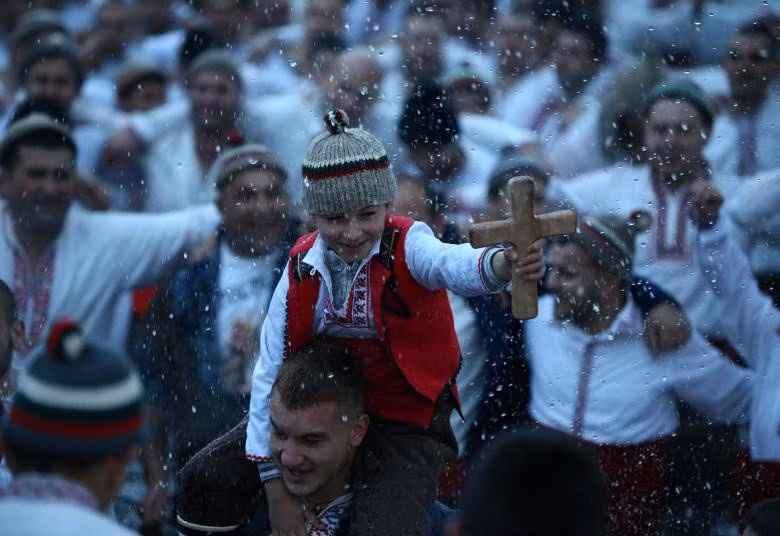 Một cậu bé cầm thánh giá bằng gỗ khi những người đàn ông nhảy múa trong vùng nước băng giá của sông Tnudzha trong Lễ Hiển Linh ở thị trấn Kalofer, Bulgaria. Hàng nghìn tín đồ Cơ đốc giáo Chính thống đã ngâm mình trong các hồ và sông băng trên khắp Bulgaria để tìm thánh giá được các linh mục tạo tác trong các nghi lễ kỷ niệm lễ rửa tội của Đức Kitô.