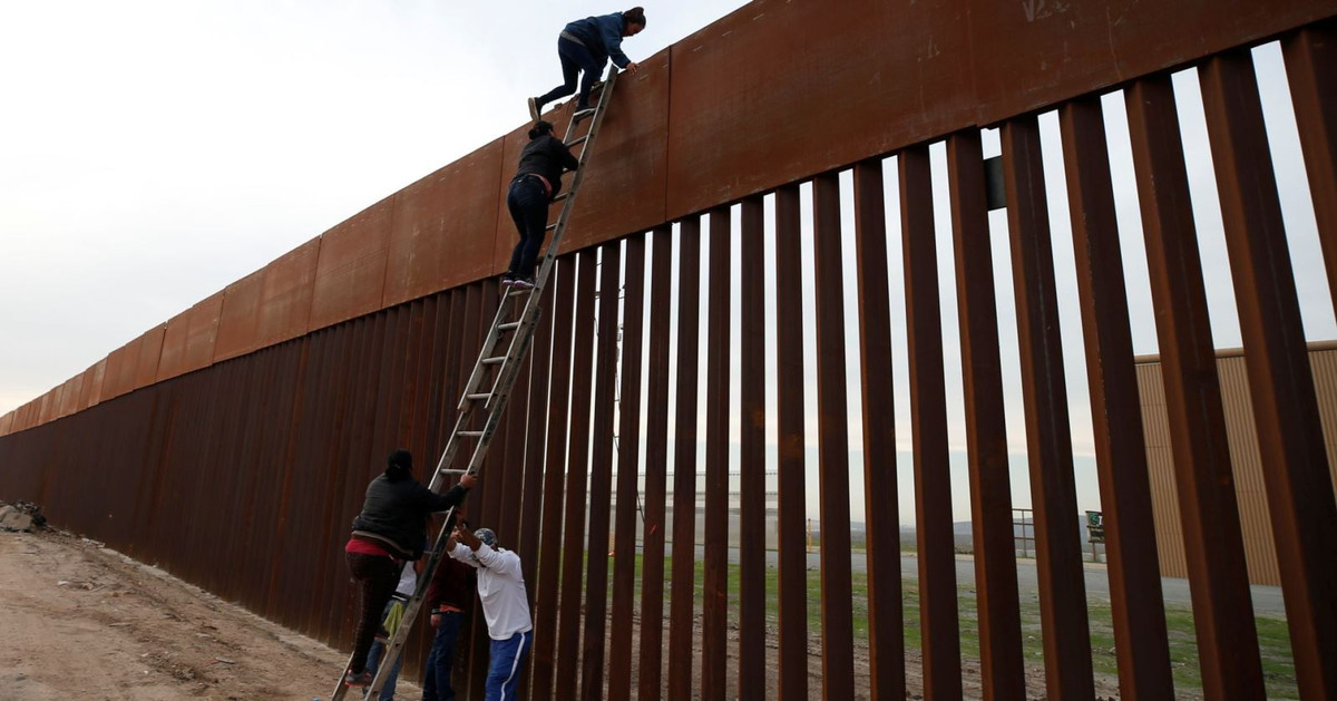 Người di cư từ Honduras tìm cách trèo qua hàng rào biên giới để xâm nhập trái phép từ Mexico vào Mỹ ngày 21/12/2018. Ảnh: Reuters