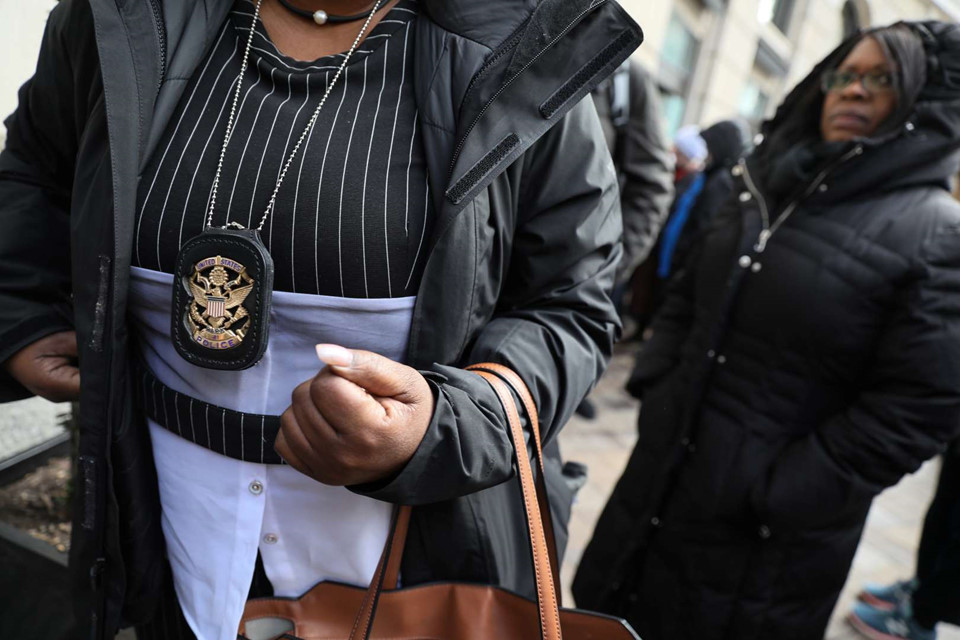 Một sĩ quan Cảnh sát Công viên Mỹ đeo huy hiệu để chứng minh cô là nhân viên liên bang khi cô và các đồng nghiệp tới nhận thực phẩm tươi và cà phê tại World Central Kitchen, một nhà bếp tình nguyện khẩn cấp được đầu bếp Jose Andres điều hành ở Washington, ngày 16/1. Hàng trăm nghìn công nhân liên bang phải nghỉ việc hoặc làm việc mà không được trả lương đang phải vật lộn để sống qua ngày trong thời gian chính phủ đóng cửa.