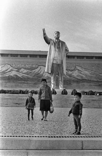 Một người phụ nữ và hai đứa trẻ đứng trước một bức tượng mạ vàng cao 23 mét của nhà lãnh đạo Kim Il Sung.