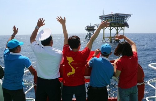 Các thành viên trong đoàn công tác giơ cao lá cờ để "truyền lửa" niềm tin chiến thắng của đội tuyển đến cán bộ, chiến sĩ Nhà giàn DK1/14 (Cụm Tư Chính)