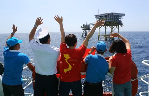 Các thành viên trong đoàn công tác giơ cao lá cờ để "truyền lửa" niềm tin chiến thắng của đội tuyển đến cán bộ, chiến sĩ Nhà giàn DK1/14 (Cụm Tư Chính)