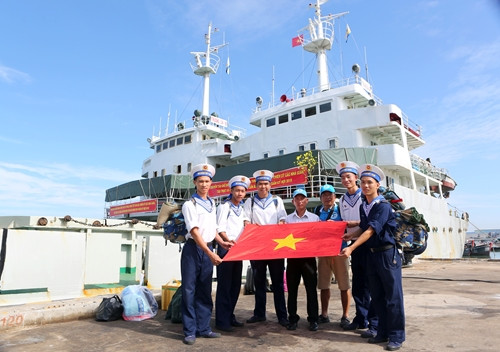 Các thành viên của CLB "Tuổi trẻ vì biển đảo quê hương" và chiến sĩ Vùng 2 Hải quân chụp ảnh cùng lá cờ trước giờ lên đường