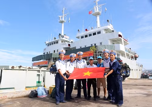 Các thành viên của CLB "Tuổi trẻ vì biển đảo quê hương" và chiến sĩ Vùng 2 Hải quân chụp ảnh cùng lá cờ trước giờ lên đường