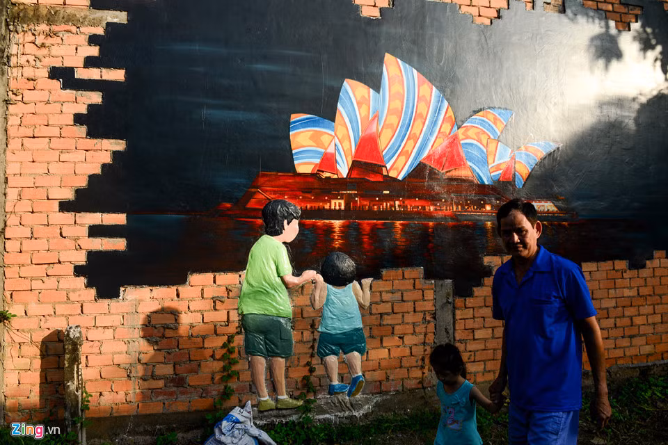 Buổi chiều, ông Trần Thanh Sơn dắt cháu tham quan những bức tranh vẽ trong làng.