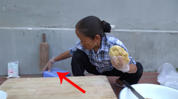 Trong quá trình làm bánh, dù đã đeo găng tay để giữ vệ sinh nhưng bà Tân lại dùng nguyên bàn tay đang đeo găng để kéo ghế ngồi, sau đó lập tức cho vào nhào bột.