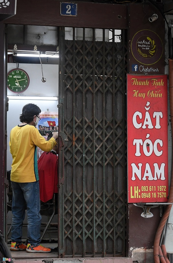 Hiệu cắt tóc trên phố Nguyễn Huy Tự chỉ đóng cửa một nửa và vẫn đón khách. Dọc phố Hào Nam, nhiều tiệm cắt tóc vỉa hè vẫn hoạt động bình thường.