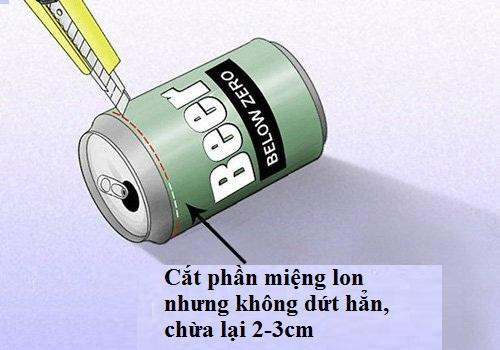 Cắt phần miệng lon nhưng cắt không hoàn toàn hết mà chừa lại gần phần lỗ khoảng 2 đến 3 cm. (Không để đứt mặt lon, tức phần miệng lon vẫn dính với thân lon)