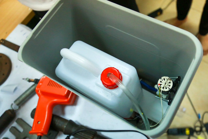 Dung dịch sát khuẩn được chứa bằng can đựng dung dịch thông thường theo quy chuẩn Bộ Y tế, được nối với 1 ống dẫn lên bộ phận phun sương tự động. Bên cạnh là máy bơm kết nối với bảng mạch.