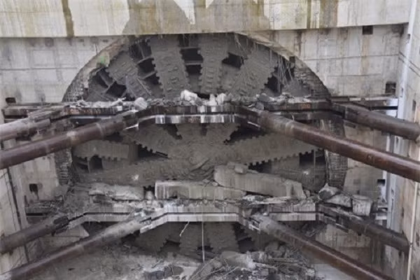 Lần đầu được vận hành vào năm 2013 và được chế tạo bởi một xưởng cơ khí Nhật Bản, chiếc máy khoan dài 99 mét và nặng 6.700 tấn này có thể đào 2,7 km chiều dài dưới mặt đất chỉ trong một tích tắc. Tuy nhiên có thể khoan xuyên đá cứng, nhưng mũi khoan này lại chào thua trước kim loại.