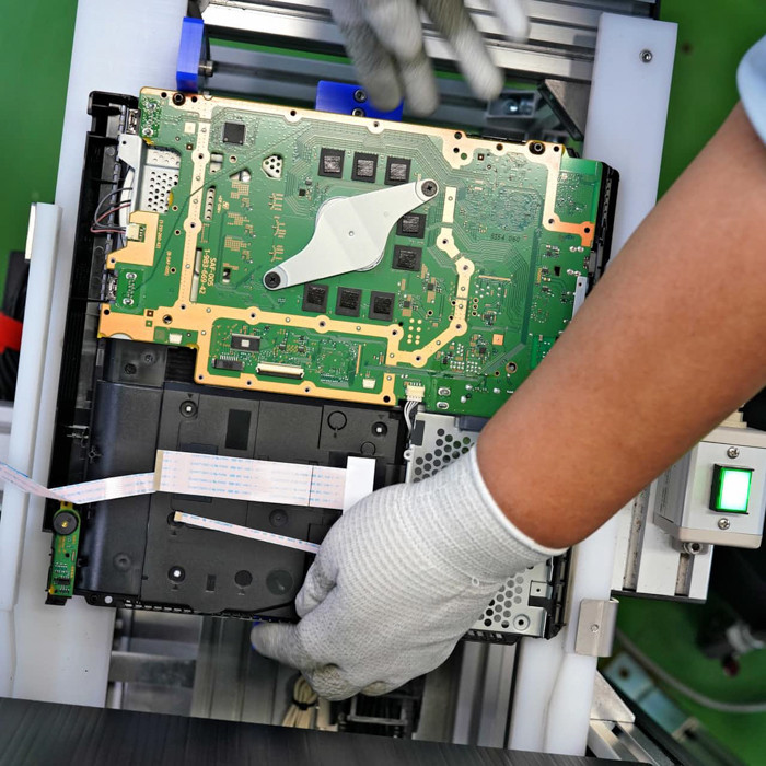 Thêm hai người làm nhiệm vụ đưa bo mạch chủ vào dây chuyền tự động, và hai người khác thì đảm nhiệm việc đóng gói cỗ máy chơi game đã sản xuất xong.