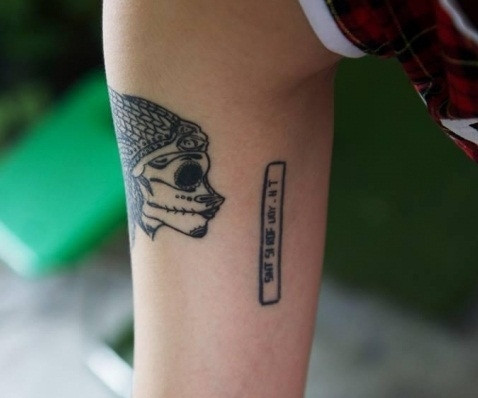 Hình xăm đầu lâu kèm dòng chữ " SIHT SI ROF UOY - HT" hay chính là cách viết ngược của dòng chữ "THIS IS FOR YOU- HT". Được biết, nhân vật HT bí ẩn này có lẽ đã từng là một người vô cùng quan trọng với nữ game thủ xinh đẹp.