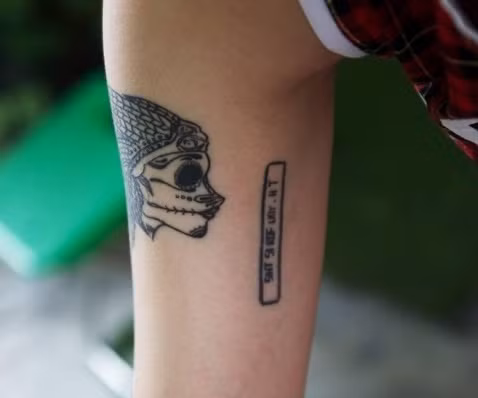 Hình xăm đầu lâu kèm dòng chữ " SIHT SI ROF UOY - HT" hay chính là cách viết ngược của dòng chữ "THIS IS FOR YOU- HT". Được biết, nhân vật HT bí ẩn này có lẽ đã từng là một người vô cùng quan trọng với nữ game thủ xinh đẹp.