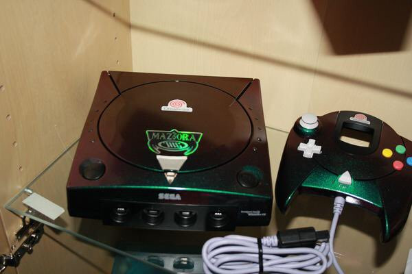 Dreamcast Maziora mang màu xanh lá cây, nhưng thực chất chiếc máy game hiếm hoi này có vỏ ngoài mang phong cách hologram xanh la tím bắt mắt. 6000 USD (khoảng 139,5 triệu đồng) là mức giá khủng của bộ game gồm một chiếc móc chìa khoá mũ bảo hiểm, một bộ sticker hình dán và một tấm hộ chiếu giấc mơ.