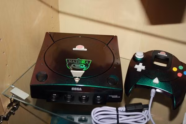 Dreamcast Maziora mang màu xanh lá cây, nhưng thực chất chiếc máy game hiếm hoi này có vỏ ngoài mang phong cách hologram xanh la tím bắt mắt. 6000 USD (khoảng 139,5 triệu đồng) là mức giá khủng của bộ game gồm một chiếc móc chìa khoá mũ bảo hiểm, một bộ sticker hình dán và một tấm hộ chiếu giấc mơ.