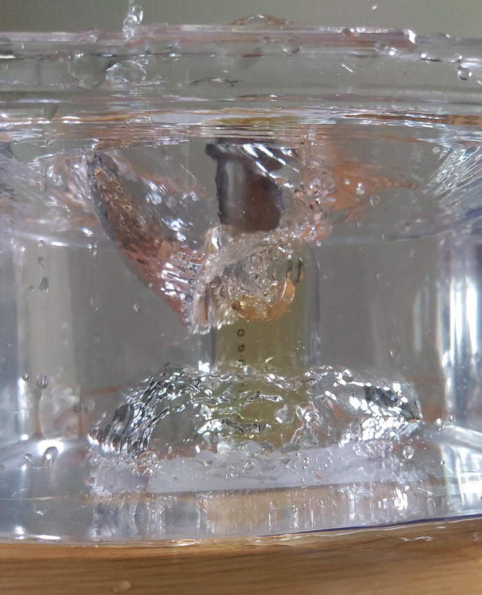 Chiếc nút chai chả chìm vào trong chậu nước trong suốt tạo thành từng bọt nước, bọt khí.