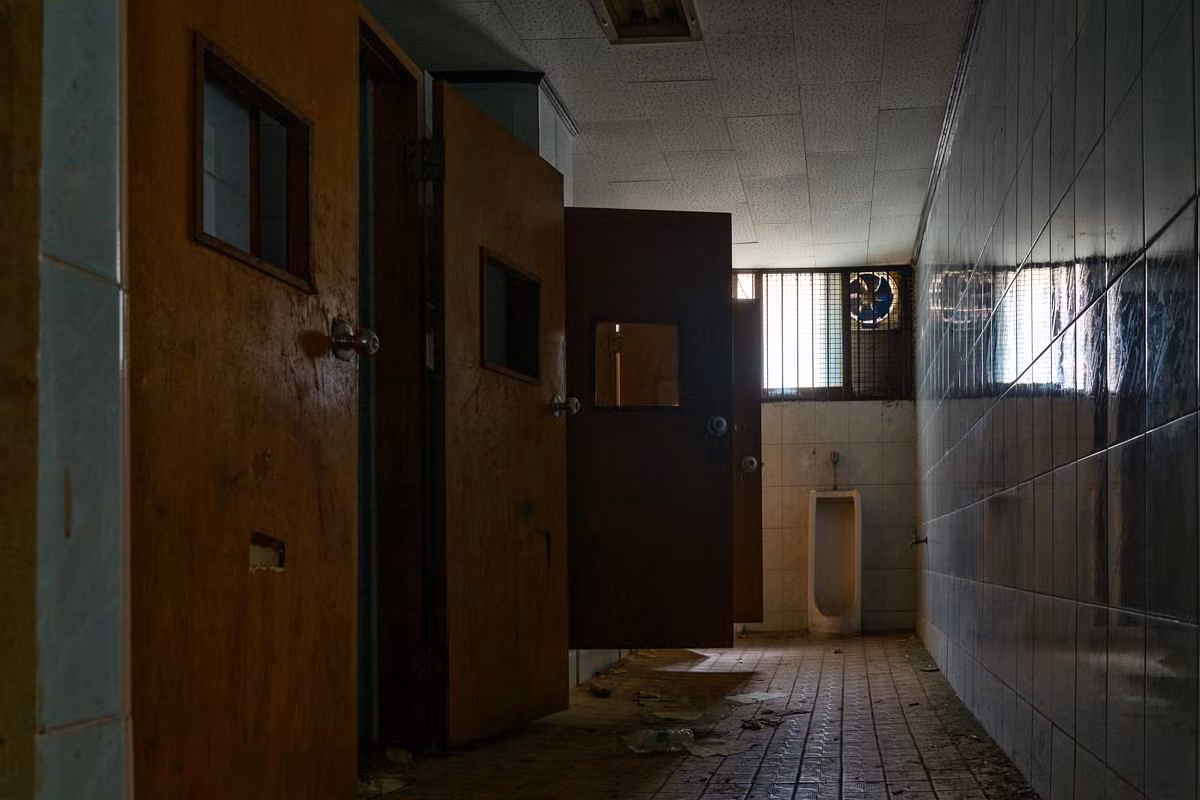 Nhà vệ sinh với những bức tường hoen ố, cánh cửa hỏng và thực sự mang một màu sắc ảm đạm, u ám.