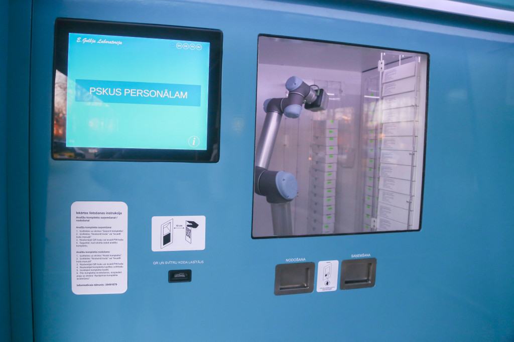 Một tay robot bên trong trạm đưa bộ test coronavirus cho người dùng đứng ở cửa trước của nó và sau đó thu thập mẫu, lưu trữ chúng trong một giá đỡ khác để phân tích.