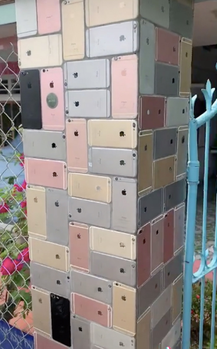 Phần cánh cổng thì vô cùng bình thường như bao căn nhà khác thế nhưng khi zoom vào hai bên cột tường thì người xem bất ngờ nhận ra nó không phải được ốp bằng gạch hay trát bê tông mà lại toàn là iPhone được đính trên đó.