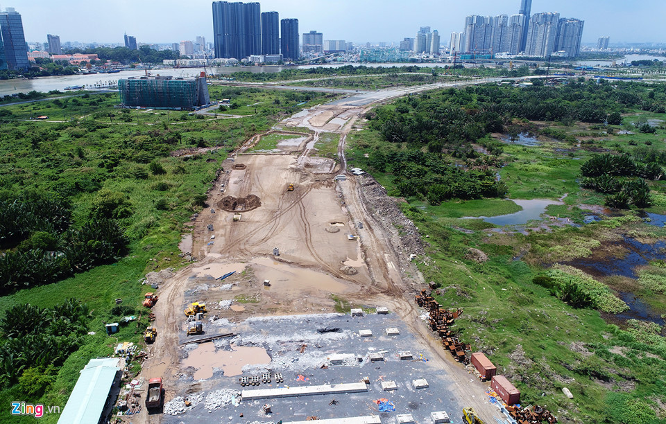 Nhưng một đoạn dài của tuyến giữa trung tâm khu đô thị (R1) hiện vẫn chỉ là nền đất. Tuyến đường này thuộc đường cấp 1, là trục xương sống kết nối các khu chức năng của Thủ Thiêm. Hạng mục đường vượt qua cửa hầm Thủ Thiêm vẫn đang ngổn ngang. Ảnh: Zing.