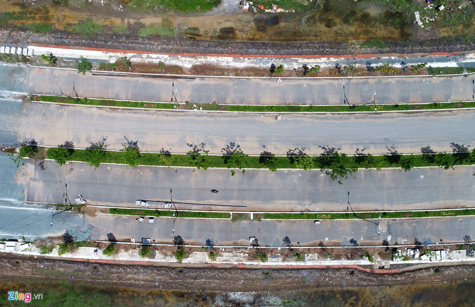 Theo khảo sát của Zing, sau 5 năm đầu tư, 4 con đường trong đô thị mới Thủ Thiêm hiện bị chậm tiến độ khi một số hạng mục vẫn ngổn ngang. Chủ đầu tư đang ngừng thi công vì chưa có mặt bằng. Cụ thể, tuyến đường R1 có mặt cắt ngang 55 m, 6 làn xe. Tại các phần đã thi công xong, đơn vị đầu tư đã cho trồng cây, lắp hệ thống chiếu sáng... Ảnh: Zing.