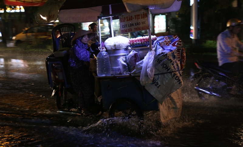Người phụ nữ suốt từ chiều đến tối khuya không bán được hàng vì mưa lớn, đành lủi thũi trở về nhà trọ trong đêm mưa.
