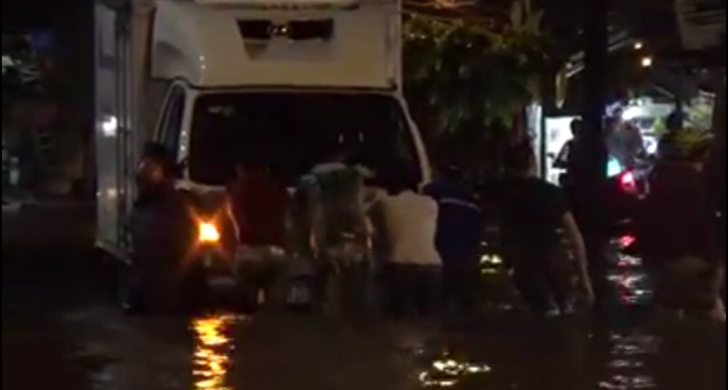 Một chiếc xe tải bị nước ngập gây chết máy giữa biển nước. Người dân địa phương đã chung tay giúp đỡ tài xế đẩy xe thoát khỏi vùng ngập.