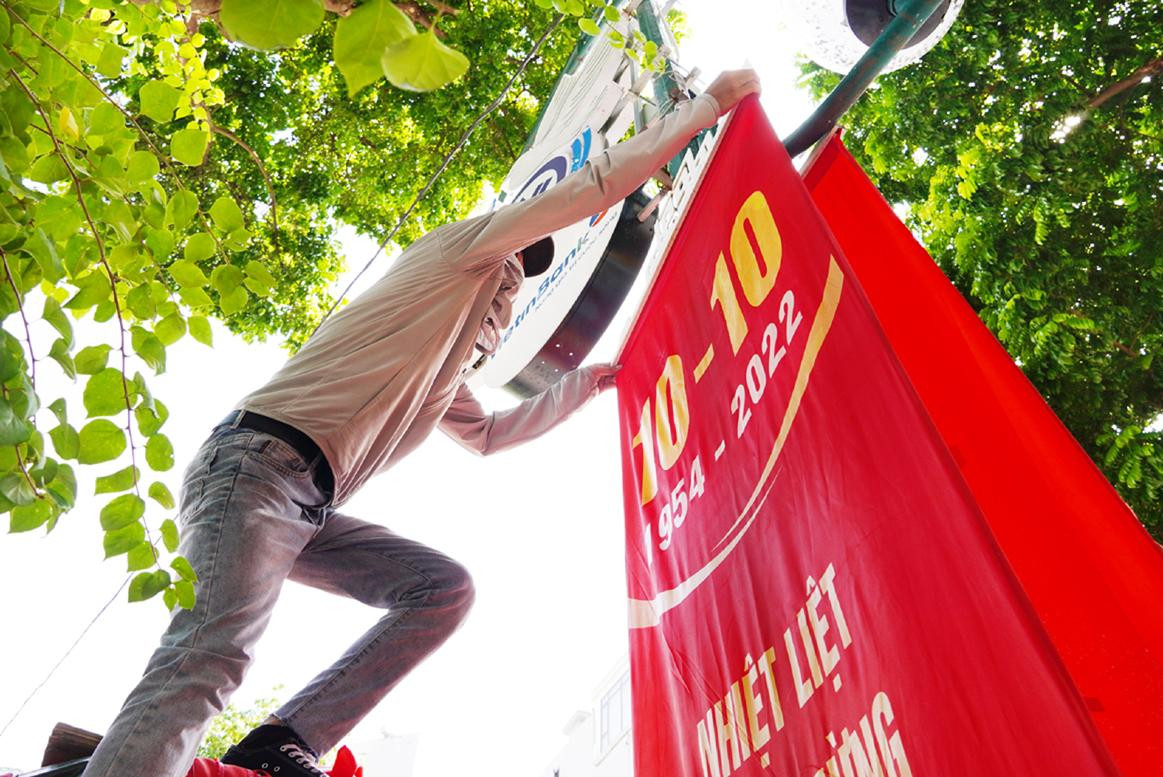 Công nhân khẩn trương treo lắp các biểu ngữ trên phố Ðiện Biên Phủ.