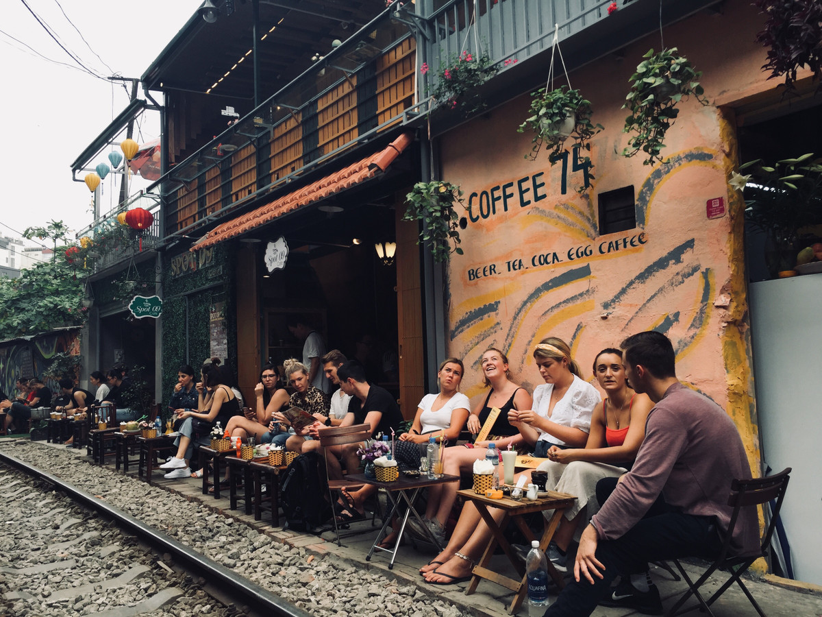 Du khách nước ngoài uống cà phê chờ tàu qua để trải nghiệm cảm giác mạnh.