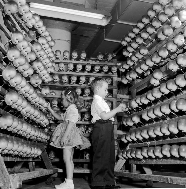 Hai đứa trẻ tham quan nhà máy làm búp bê. Đây là khu vực làm phần đầu búp bê.