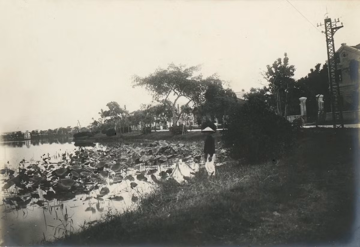 Một góc hồ Hoàn Kiếm. Một người dân đứng bên bờ ngắm cảnh và phía xa là Tháp Rùa.