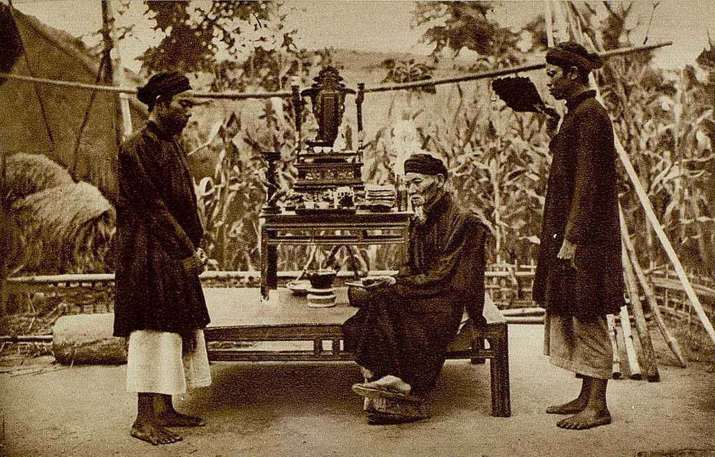 Ông lão gia đình quý tộc người Việt xưa ngồi trước sân nhà, hai bên là hai người hầu. Ảnh: Gallica.bnf.fr.