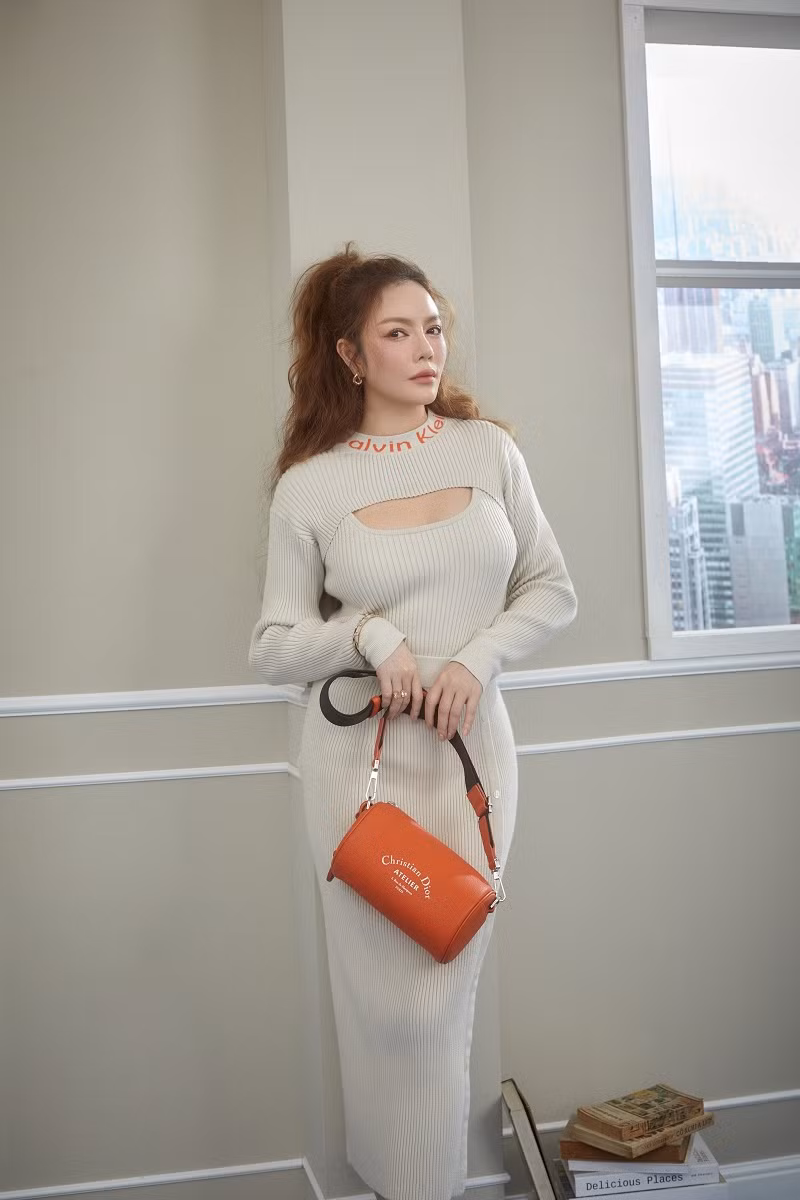 Với bộ váy dệt kim tông trắng xám, Lý Nhã Kỳ chọn phối túi cam trẻ trung của Dior, sành điệu với trang sức kim cương.