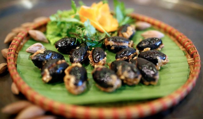 Cho 1/2 lít nước vào nồi đun sôi, nêm khoảng 3 thìa canh muối vào khuấy đều, nhấc ra khỏi bếp để nguội còn khoảng 75 độ, cho trám vào ngập nước, đậy vung để nguyên tại chỗ (còn gọi là om trám) và để hôm sau dùng. Trám mềm tay rồi vớt ra, bổ dọc thân quả lấy thịt, bỏ hột. Thịt xay nhỏ, mộc nhĩ, nấm hương rửa sạch băm nhỏ, thêm một chút hành khô đập dập. Trộn đều tất cả các nguyên liệu, nêm một chút gia vị. Nhồi hỗn hợp thịt đã trộn vào quả trám và xếp ra đĩa.