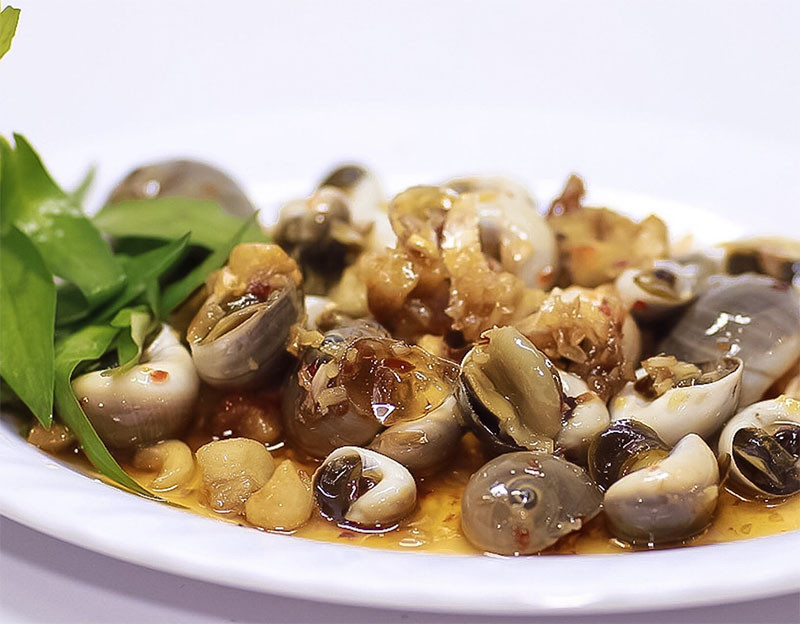 Cách làm: Đun một nồi nước sôi, thêm vào 15gr gừng cắt lát đập dập, cho ốc vào trụng sơ 2 phút sau đó vớt ra rửa sạch. Cho vào nồi 20gr bơ lạt, 2 muỗng canh nước mắm cùng 3 muỗng canh đường. Đảo đều cho đường tan, đun cho nước sốt sôi lên và hơi kẹo lại. Trút ốc mỡ vào, thêm 50gr tỏi phi vàng, đảo đều rồi để khoảng 2 phút cho ốc thấm gia vị và thơm mùi tỏi rồi nhắc xuống.