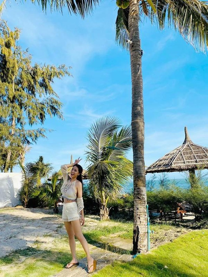 Nữ ca sĩ Hải Băng ăn mặc trẻ trung và tạo dáng nhí nhảnh bên bãi biển.