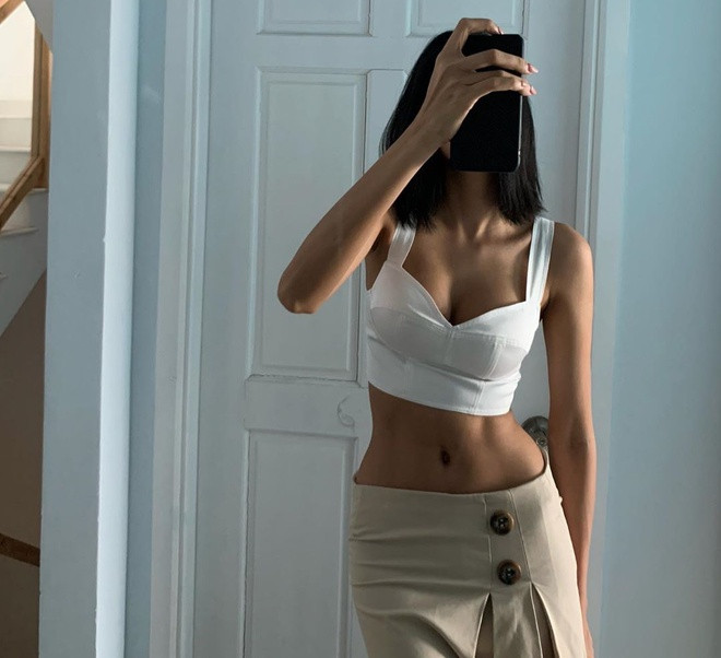 Chuộng gu thời trang hở eo thon, Hoàng Thuỳ diện mẫu crop top gam trắng xẻ sâu phối cùng chân váy bó sát đầy cá tính và gợi cảm.