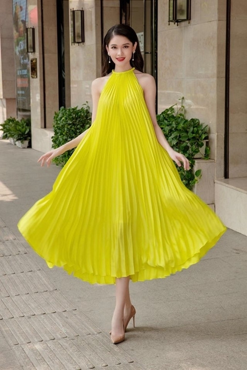 Á hậu Thùy Dung tung váy xếp ly vàng rực rỡ trên đường phố.