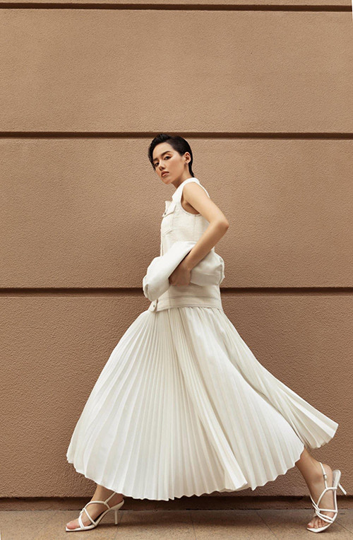 Vẫn áp dụng công thức phối đồ tiệp sắc trắng, Khánh Linh giúp hình ảnh của cô trở nên cuốn hút hơn với thiết kế váy xếp ly đúng trend 2020.