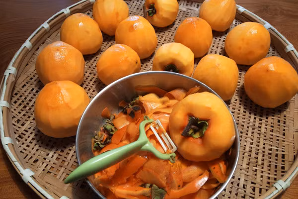 Sau đó thì bạn lấy chỉ buộc cuống trái hồng lại với nhau. Bạn chuẩn bị một nồi nước có pha sẵn rượu trắng vào và đun sôi, sau đó thì cho hồng vào ngâm khoảng 2 đến 3 phút để khử trùng bề mặt trái hồng để cho hồng không bị hỏng.